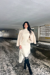 a lady in a long white sweater dress and a beige lamb coat